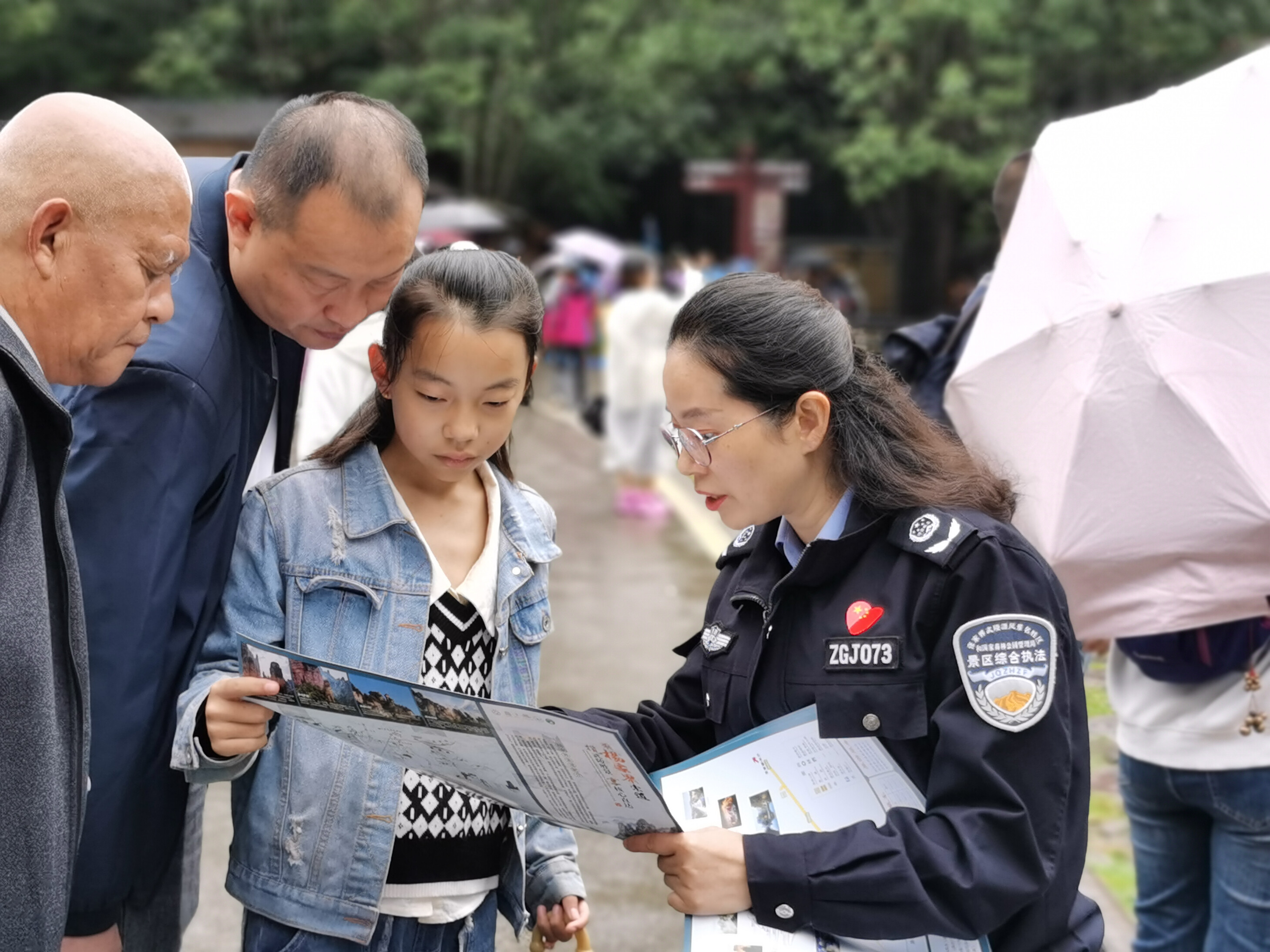 10月1日上年，金鞭溪景區(qū)管委會女子執(zhí)法隊隊員開展流動導覽服務，為游客免費贈送地圖。張娜 攝